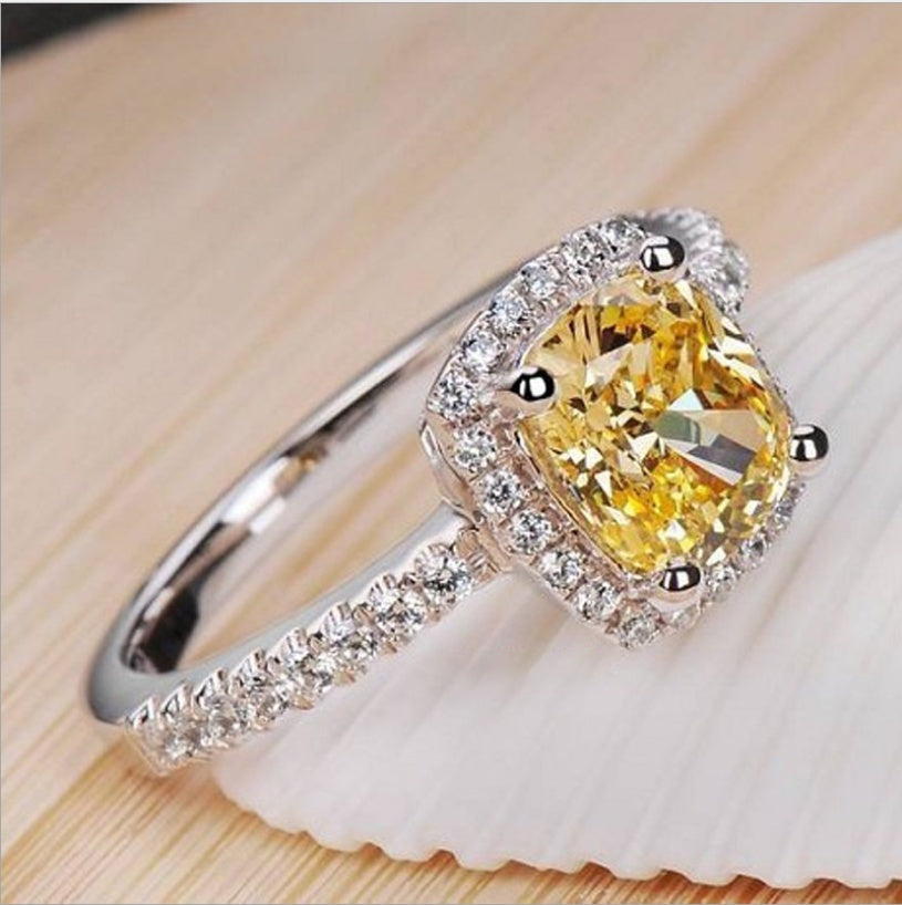 Elegant bridal engagement ring for women in white gold color with yellow centerpiece and diamond accents.