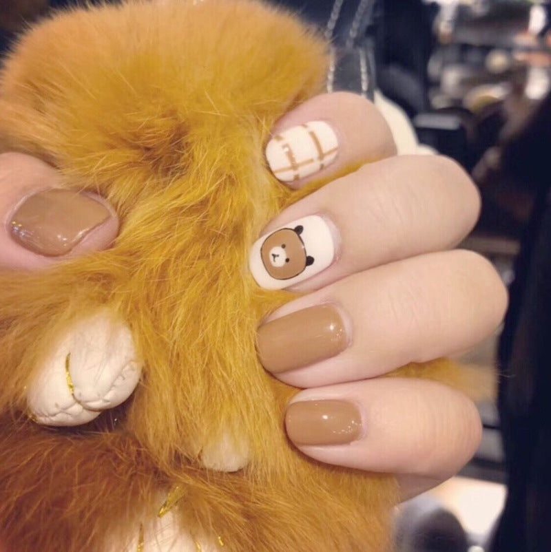 Decorative fake nails with bear and striped designs, featuring a natural brown and white color scheme.