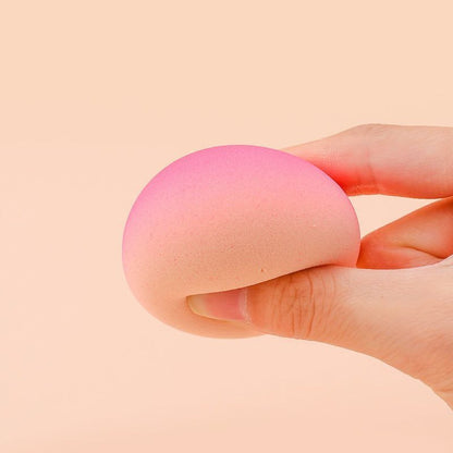 Gradient peach makeup sponge egg held in hand.