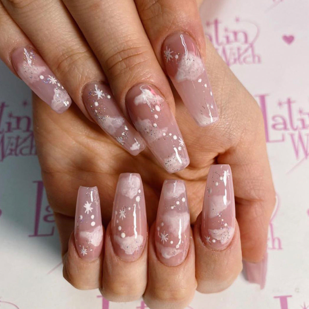 Soft pink false nails with snowflake design, perfect for stylish nail art.