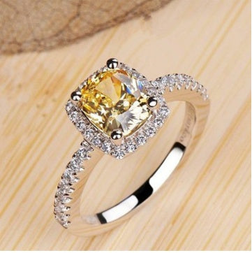 Elegant silver engagement ring for women with yellow gemstone and diamond accents.