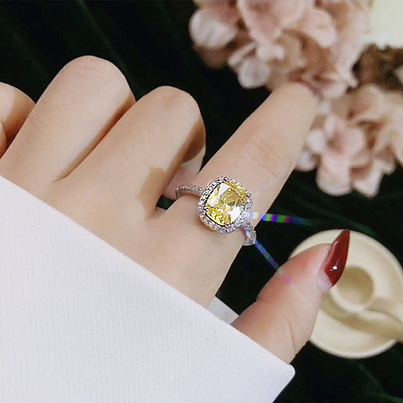 Elegant women's engagement ring in white gold color with a yellow gemstone.