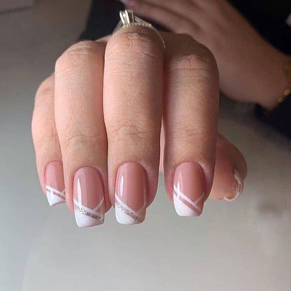 Oblique French manicure finished fake nails on hand, showcasing elegant design.